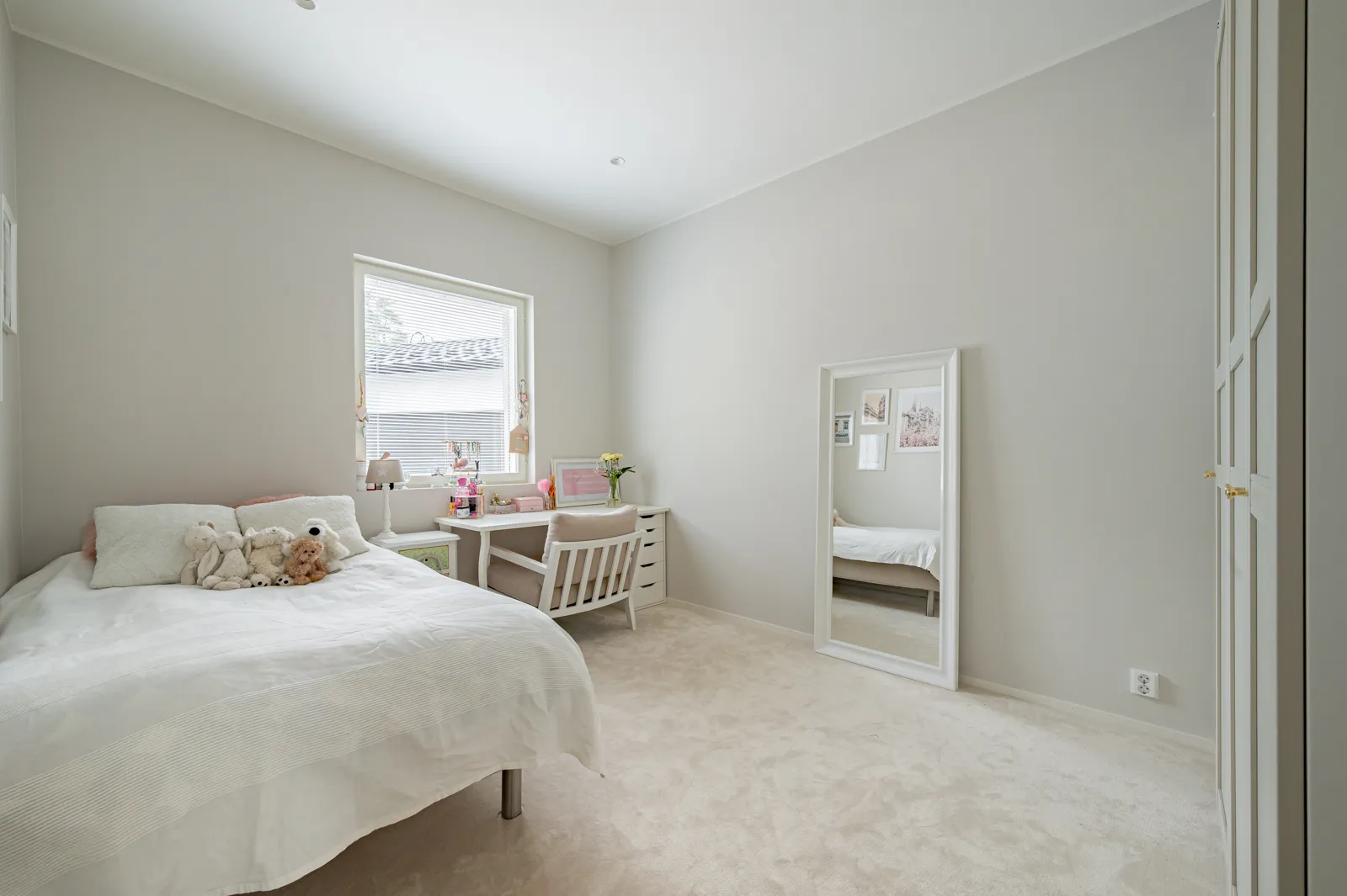 Vaaleassa makuuhuoneessa on sänky, työpöytä, peili ja vaatekaappi, ja huone on valoisa.