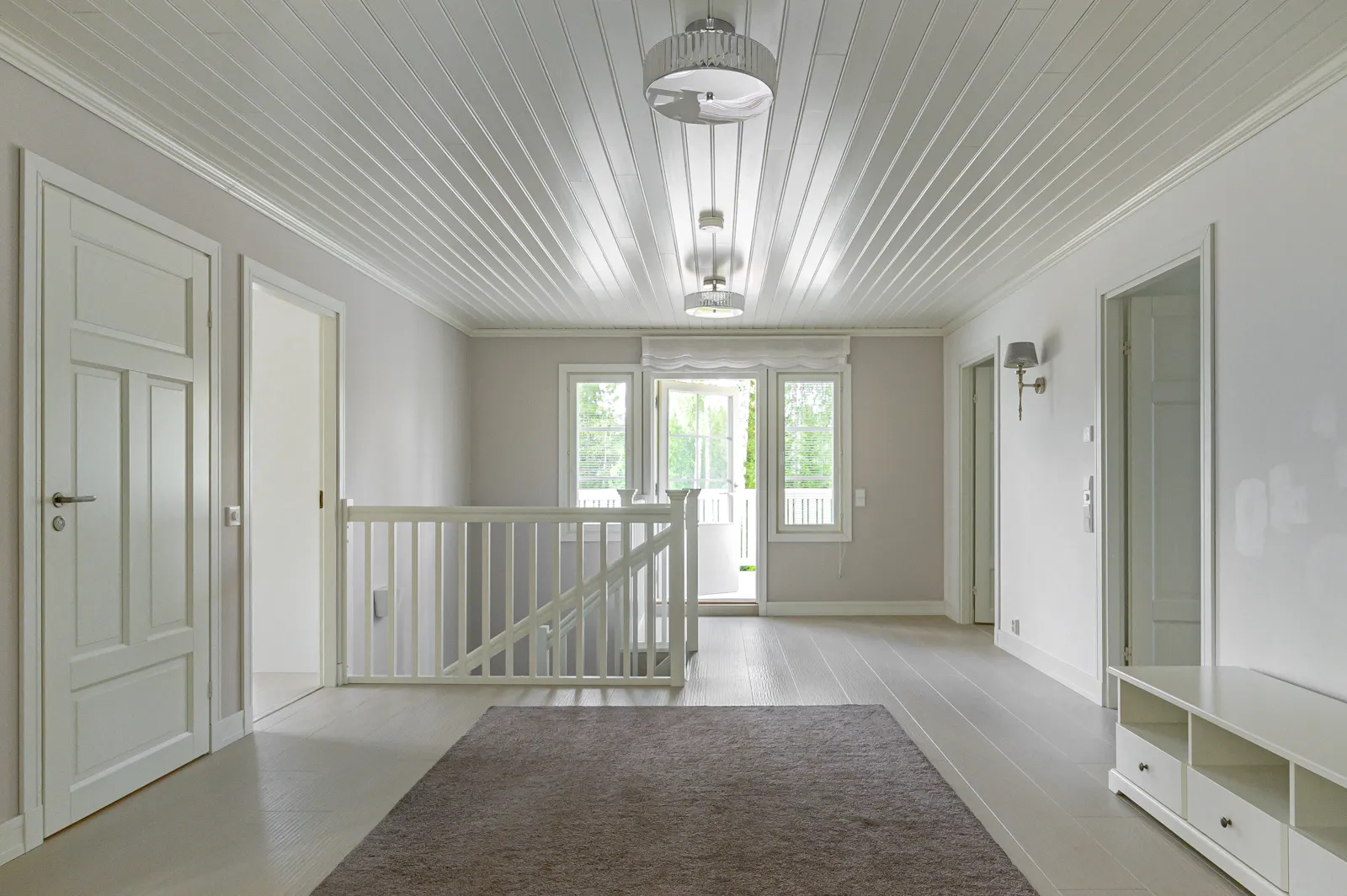 Vaaleassa huoneessa on valkoinen katto, ovet, kaiteet ja matto. Huoneessa on myös ikkuna ja valaisimia.